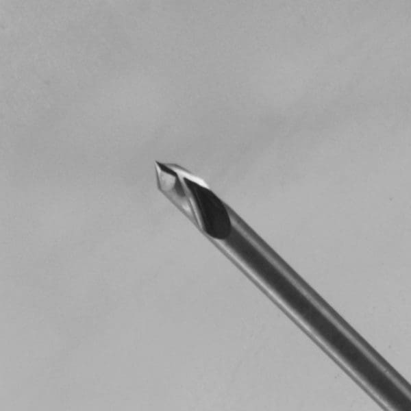 A close-up photograph of a polished metal V-bit or engraving bit featuring sharp angled cutting edges at the tip, positioned diagonally against a soft gray background.